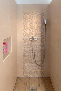 y baño con ducha y pared de azulejos. en Apartments Grahek en Liubliana