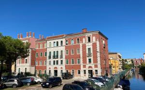 a large brick building with cars parked next to a canal at Cà Laguna Lido in Venice-Lido