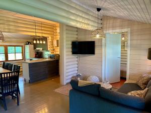 a living room with a couch and a table and a kitchen at Kuusiston majatalo in Kuusisto