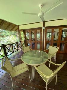 un patio con una mesa de cristal y sillas en una terraza en Bamboo Forest Beach Villa, Nongsa, en Telukmataikan