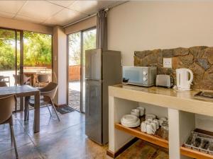 a kitchen with a stainless steel refrigerator and a table at Orange River Rafting Lodge in Kotzeshoop