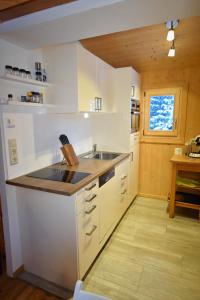 a kitchen with white cabinets and a sink at Zirbenwald Chalet in Turracher Hohe