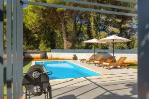 una piscina con parrilla, sillas y sombrilla en Modern villa Eva with pool and 2 bedrooms in Tar, en Tar