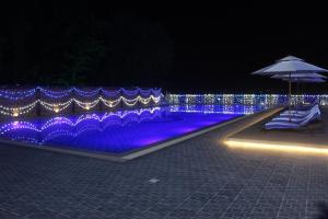 a swimming pool with blue lights and an umbrella at Brisa Marina CBC Resort ব্রিসা মেরিনা সিবিসি রিসোর্ট in Patenga