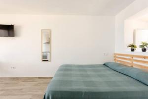 um quarto branco com uma cama com um cobertor verde em Blue Sky Apartment em Torremolinos