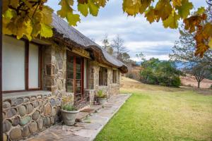 a stone house with potted plants in front of it at Lolambazo Country House & Cottage - Giants Castle Drakensberg in Mahlutshini