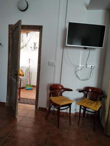 蒂亞斯的住宿－Ca' Anibal，一间设有两把椅子和一台墙上的电视的房间