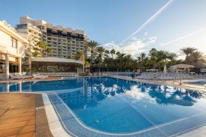 Una gran piscina con sillas y un edificio. en Grupotel Orquidea, en San Agustín