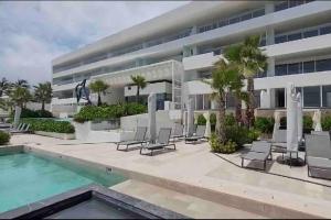 un edificio con sedie e una piscina di fronte ad esso di Ikaroa Luxury apartment direct on the beach AirB&B ad Acapulco