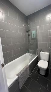 a bathroom with a toilet and a tub and a shower at Peaceful bright city hide away with parking in London