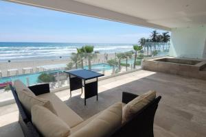 un soggiorno con divano, tavolo e spiaggia di Ikaroa Luxury apartment direct on the beach AirB&B ad Acapulco