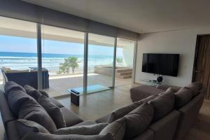 un soggiorno con un grande divano e una TV di Ikaroa Luxury apartment direct on the beach AirB&B ad Acapulco