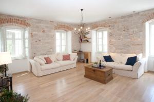 a living room with two white couches and a stone wall at Stylish Theatre Apartments in Split