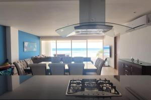 una cucina e un soggiorno con tavolo e piano cottura di Ikaroa Luxury apartment direct on the beach AirB&B ad Acapulco
