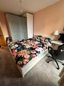 a bedroom with a bed with a floral comforter and a desk at Sunny 1bedroom flat for rent. in London