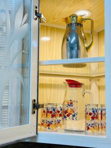 a glass cabinet with a pot and glasses in it at ENG-Murjan Apartment in Aqaba