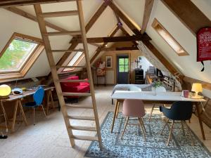 een kamer met een loft met een ladder en een tafel en stoelen bij De Windroos | Atelier Aan Zee in Groet