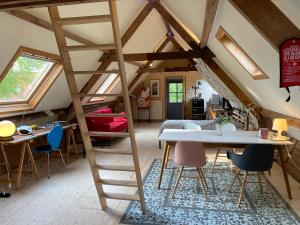 Una habitación con un altillo con una escalera y una mesa y sillas. en De Windroos | Atelier Aan Zee, en Groet