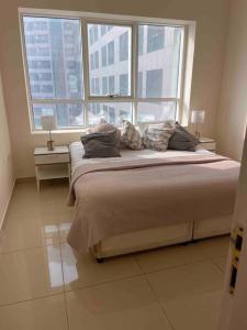 een slaapkamer met een groot bed en 2 ramen bij deluxe apartment closed to beach in Sharjah