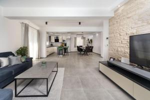 a living room with a couch and a tv at Modern villa Danica with pool in Zadar in Bibinje