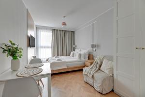 een witte slaapkamer met een bed en een bank bij Downtown Apartments Riverside Aura Island in Gdańsk