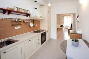 a kitchen with white cabinets and a sink and a table at Stylish Theatre Apartments in Split