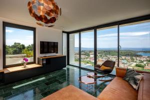 a living room with a couch and chairs and large windows at Luxury villa Mar with infinity pool in Rab in Palit