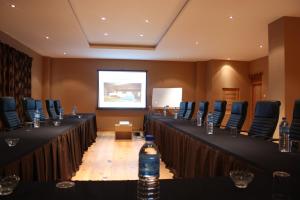 einen Konferenzraum mit Tischen, Stühlen und einem Bildschirm in der Unterkunft Udumwara Resort in Paro