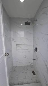 y baño con ducha y azulejos de mármol blanco. en The Moongate, en San Fernando