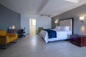 a bedroom with a bed and a desk and a chair at Green Fields Hotel, Coffee Bay in Coffee Bay