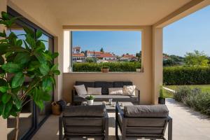 a patio with a couch and chairs and a large window at Modern villa Amoroso with pool in Porec in Nova Vas