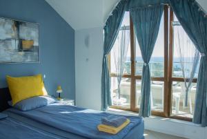a blue bedroom with a bed and a large window at Black sea Narcissus - quiet studio with amazing sea view in Varna City