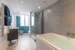 La salle de bains est pourvue d'une baignoire et d'une douche. dans l'établissement Le Lovely cosy jacuzzi centre-ville wifi, à Rouen