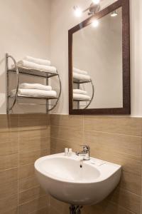 een badkamer met een wastafel, een spiegel en handdoeken bij Fleming Suites in Rome