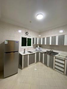 una cucina con frigorifero e lavandino in acciaio inossidabile di لوريت للشقق المخدومة a Gedda