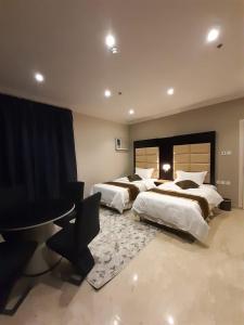 a bedroom with two beds and a table in it at لوريت للشقق المخدومة in Jeddah