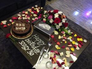 una mesa con un pastel de cumpleaños y flores en ella en أجنحة النرجس أبها, en Abha