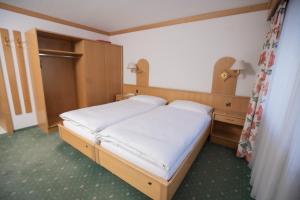 サース・アルマゲルにあるHotel Alpenhofのベッドルーム1室(白いシーツが備わるベッド1台付)