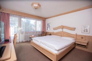 Schlafzimmer mit einem Bett, einem Schreibtisch und einem Fenster in der Unterkunft Hotel Alpenhof in Saas-Almagell
