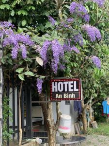 una señal frente a un árbol con flores púrpuras en Khách Sạn An Bình en Phước Lộc Xã