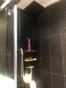 y baño con ducha y pared de azulejos negros. en Smart Lugano Apartment, en Tirana