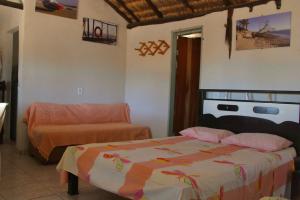 1 dormitorio con cama y sofá en Chalés Ventos de Amarração, en Ponta do Anel