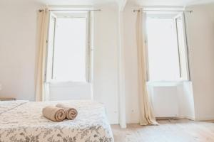 una camera da letto con due asciugamani su un letto con due finestre di 2 pièces de charme au coeur du village de CABRIS a Cabris