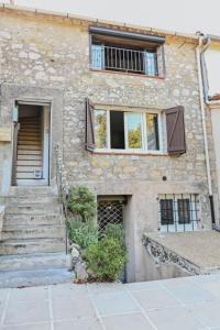 un edificio in pietra con scale e finestra di 2 pièces de charme au coeur du village de CABRIS a Cabris