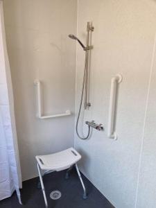 a bathroom with a shower with a stool in it at River Edge Lodges in Perth
