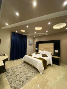 a bedroom with a large bed and a blue curtain at لوريت للشقق المخدومة in Jeddah