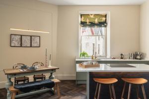 a kitchen with a sink and a counter with stools at The Old Fire Station: Heart of Kirkby Lonsdale in Kirkby Lonsdale