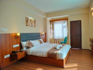 1 dormitorio con 1 cama grande y 1 silla azul en Sila Norphel Pelling en Pelling