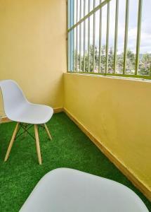 une chaise blanche assise dans une pièce avec fenêtre dans l'établissement Spacious 1br Fully Furnished with Parking Nakuru, à Nakuru