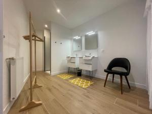 a bathroom with a sink and a black chair at Maison Particulière au Bono in Le Bono